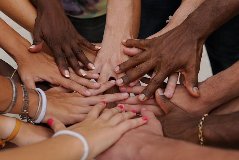 Multiple hands coming together in the middle of a circle